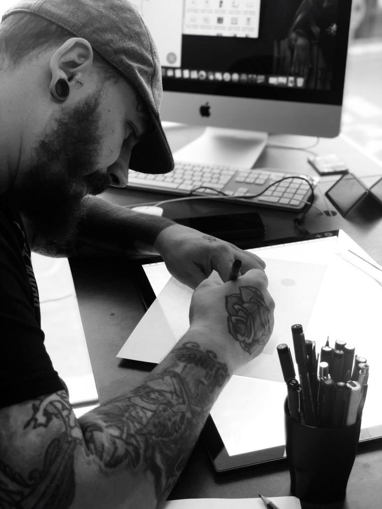 tatoueur à passa Skin'ink en train de dessiner dans le shop Elden'ink 